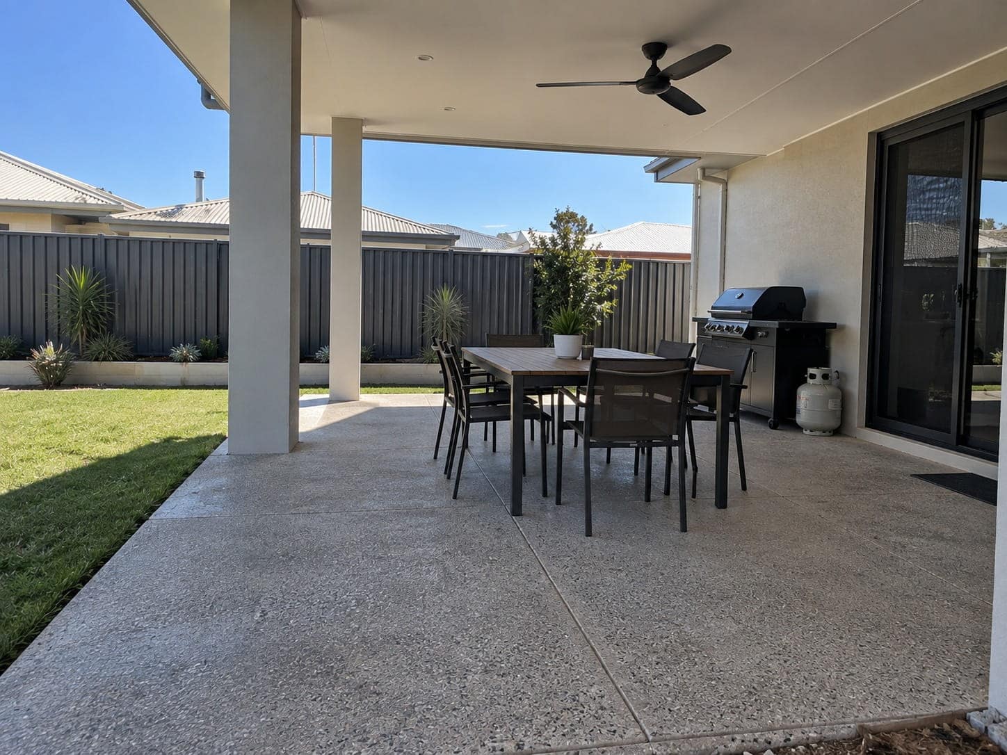 Covered alfresco at a Mandurah home with a dining setting and barbecue on an exposed aggregate floor