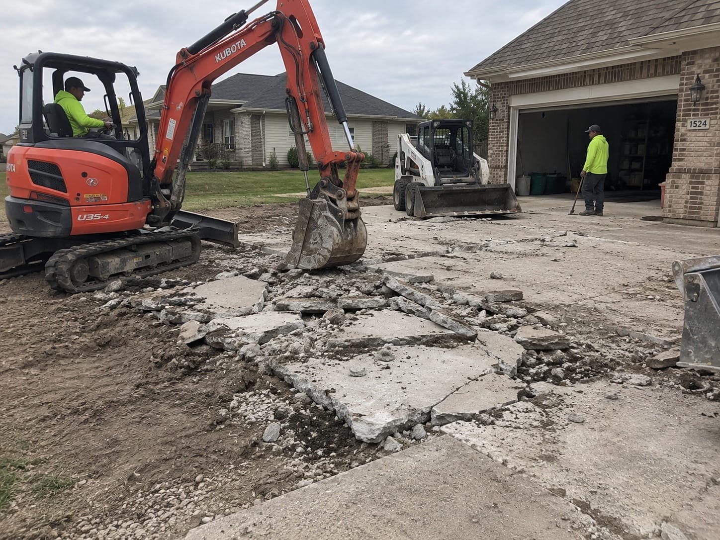 Excavator breaking out an old concrete driveway