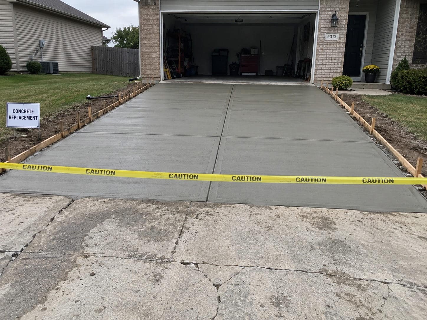 Newly poured driveway in formwork beside the old cracked concrete
