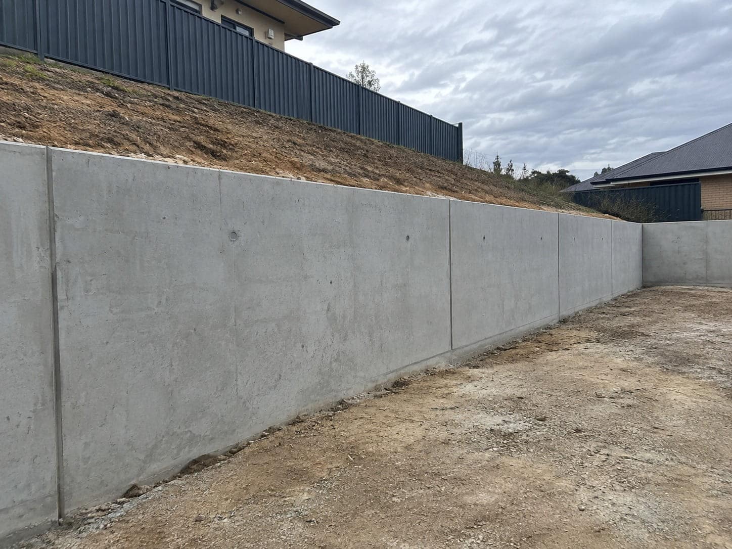 Poured concrete retaining wall stepping down along a batter on a sloping Mandurah block