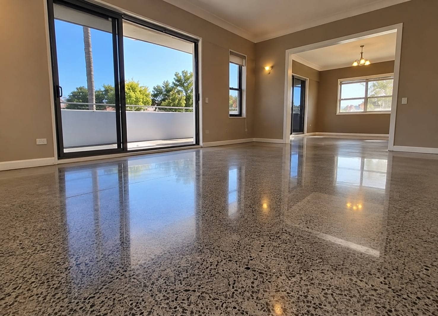 High-gloss polished concrete floor in a Mandurah canal home, reflecting light from the balcony glazing