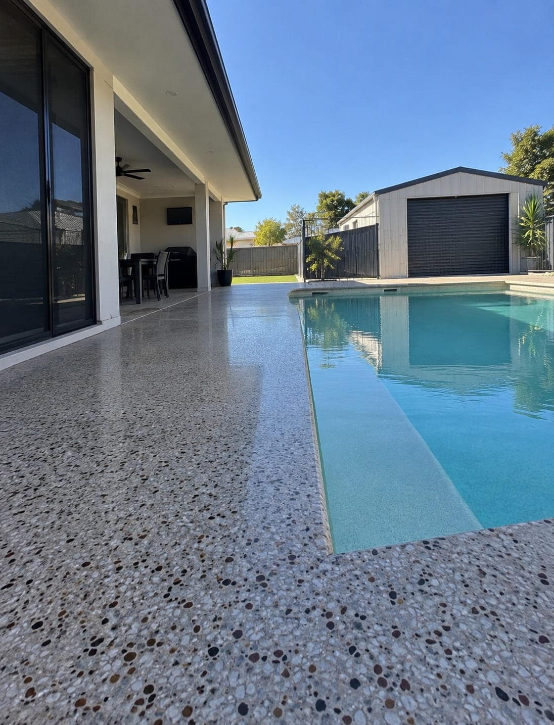 Light-toned coloured concrete pool surround beside a Mandurah backyard pool
