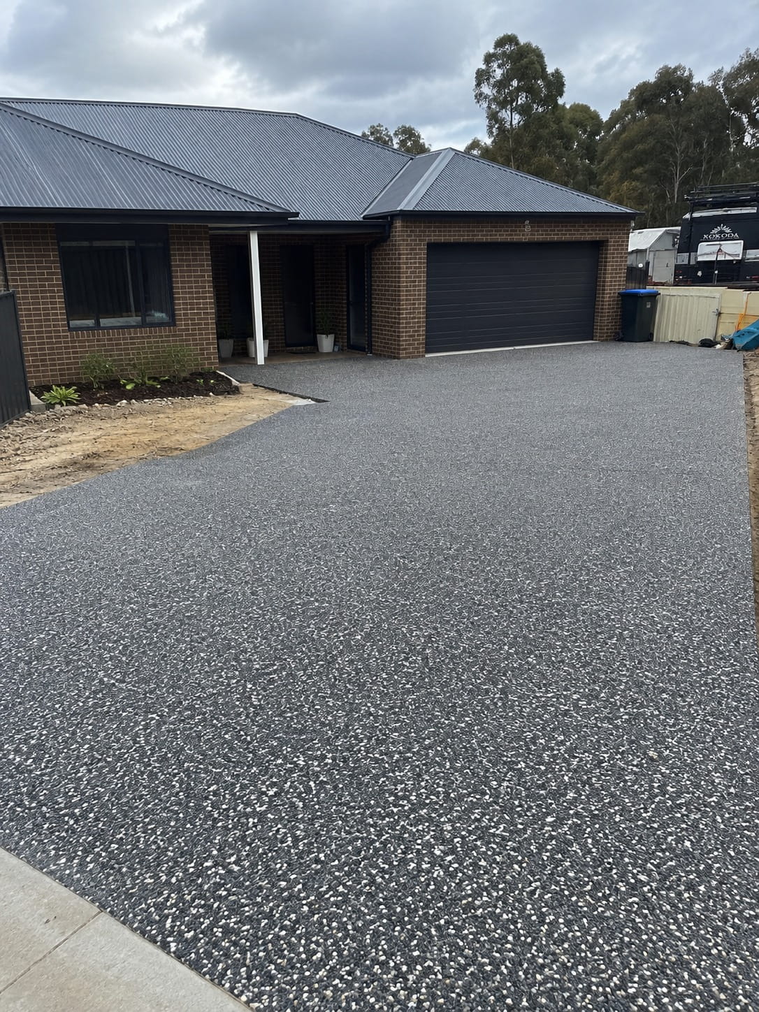 Charcoal exposed aggregate driveway at a Mandurah home, finished up to the garage door